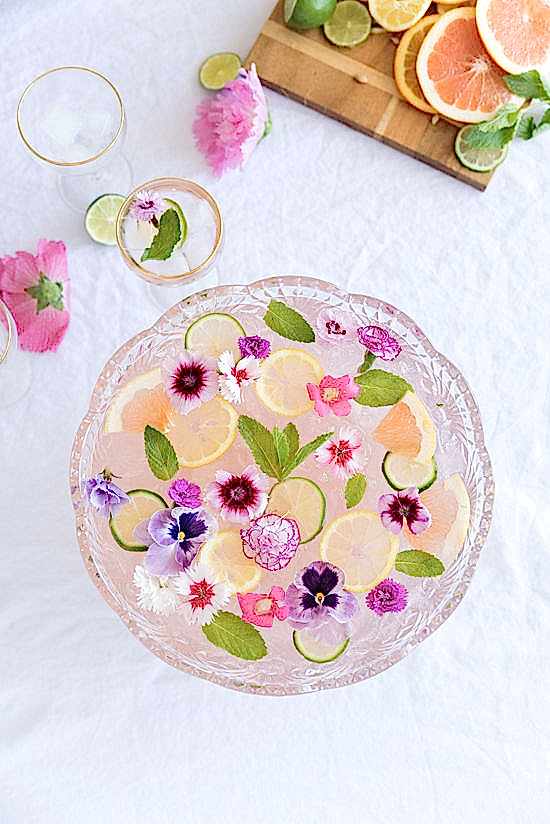 engagement party ideas for punch bowl filled with fruit and flowers on white tablecloth