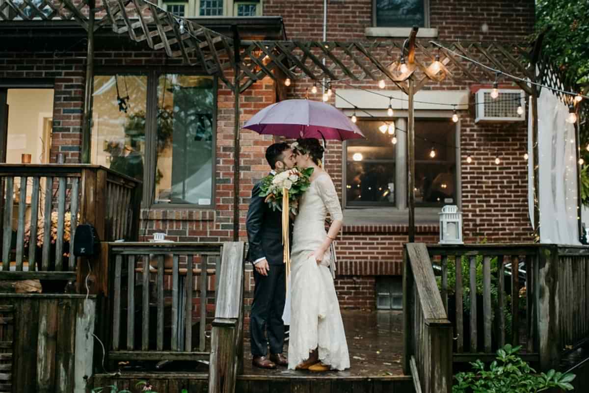 a couple kissing under an umbrella in a restaurant backyard