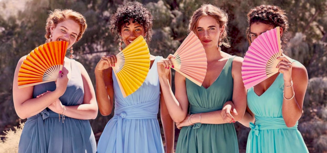 four bridesmaids holding different color paper fans in a wedding without flowers