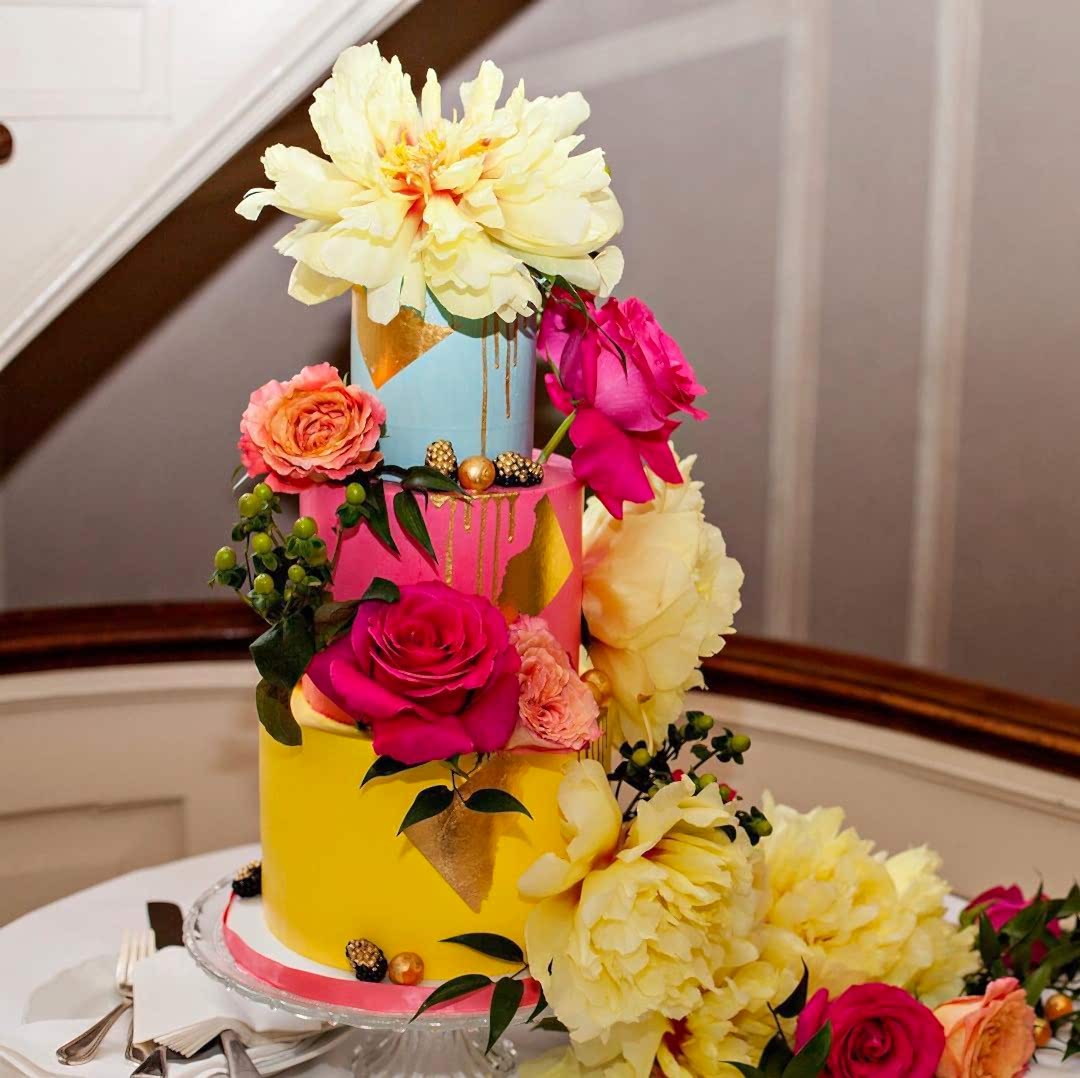 colorful 3-tiered wedding cake covered in fresh flowers