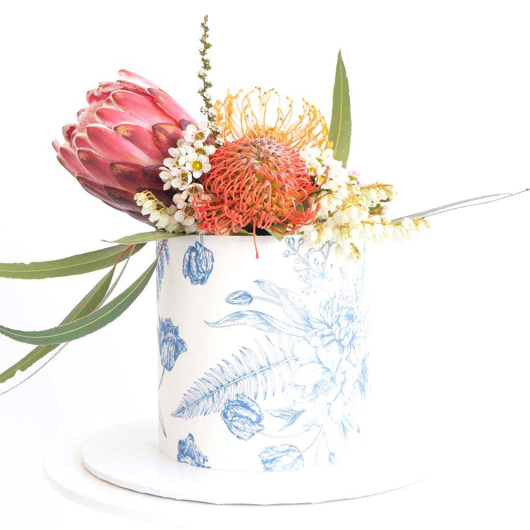 a white and blue floral printed wedding cake topped with flowers