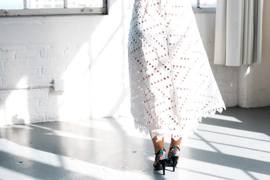 the back of a woman wearing a short wedding dress and heels from the waist down