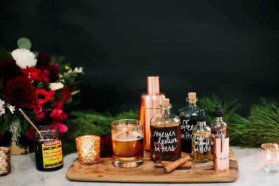 An assortment of cocktail accessories, bitters and ingredients on a wooden cutting board for bridal shower favors