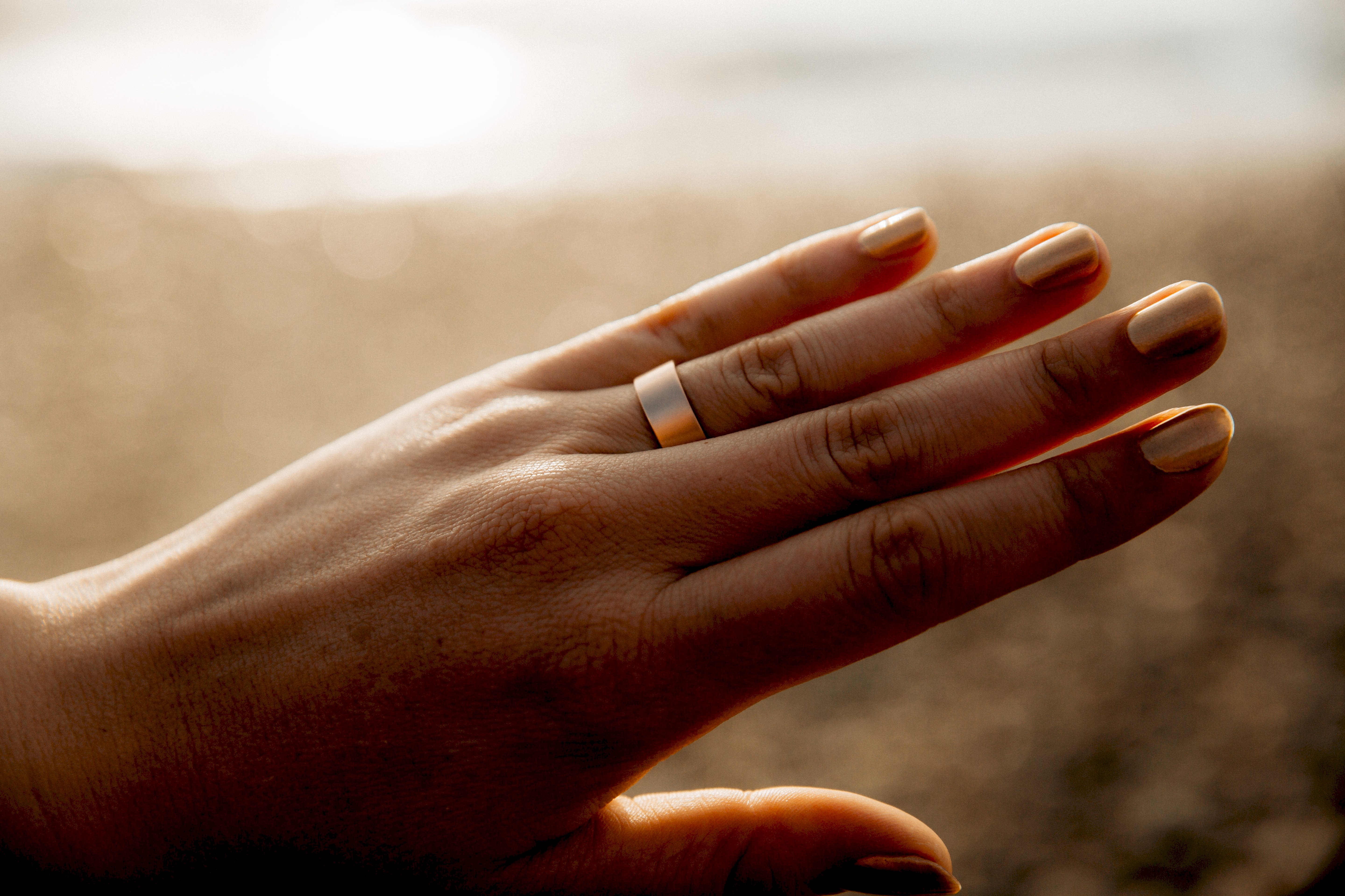 Close up of a Good Gold wedding band on a hand at sunset
