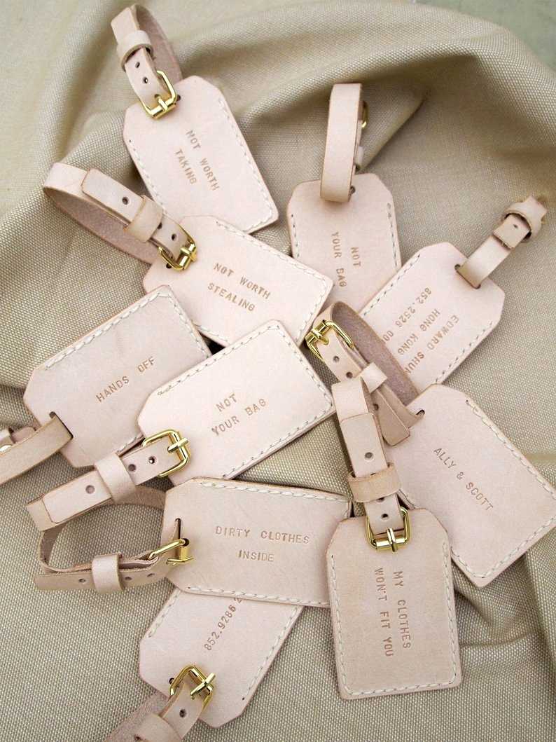 Light pink leather luggage tags and stamped with fun phrases for bridal shower favors