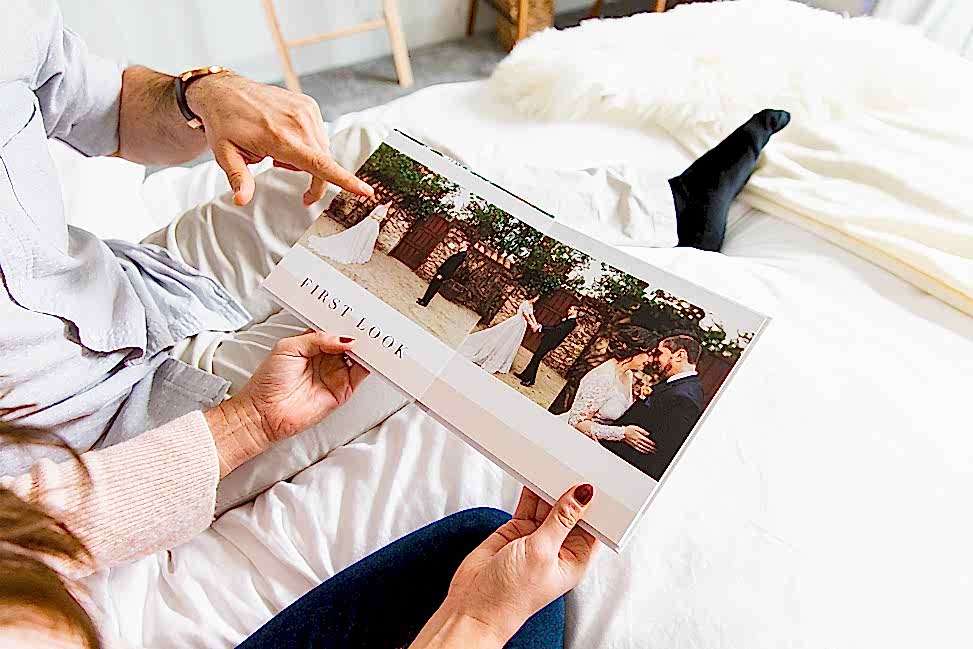 Two people are looking through a Mixbook photo album