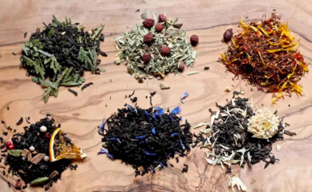 Piles of six different tea blends on a wooden table for bridal shower favors