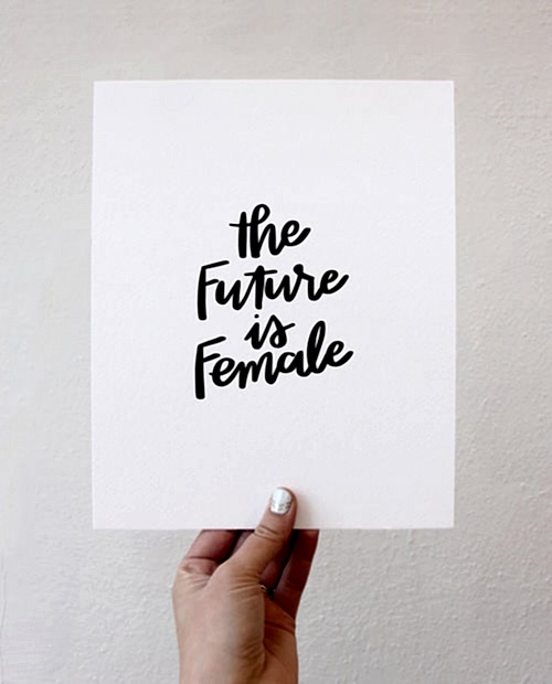 An art print saying "the future is female", held up by a hand for bridal shower favors
