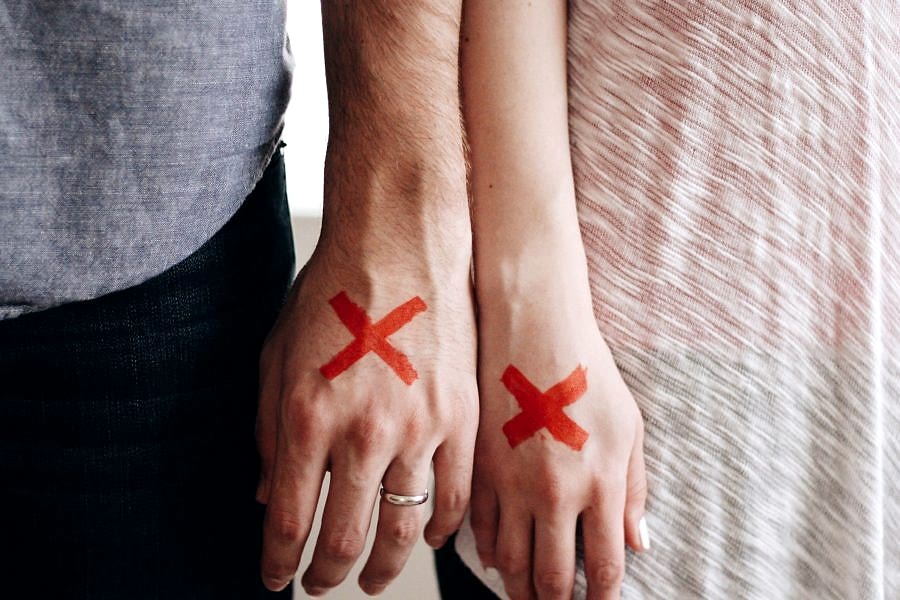 a couple stand side by side with red X's on their hands