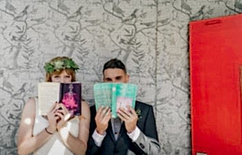 Two people hold books up to their faces, books with wedding readings in them.
