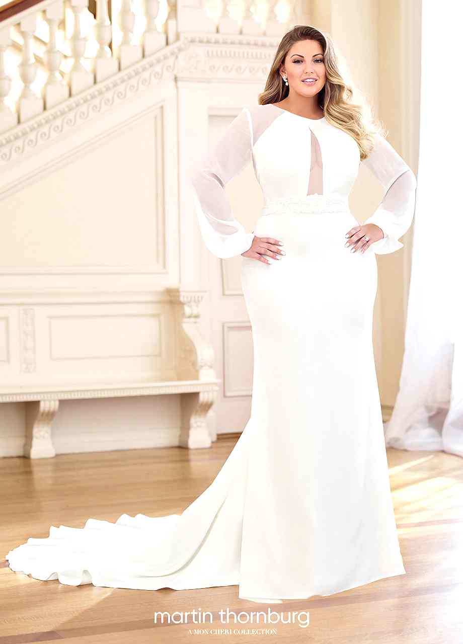 plus size blonde woman wearing a cut-out, sheer, belted wedding dress standing with her hands on her hips
