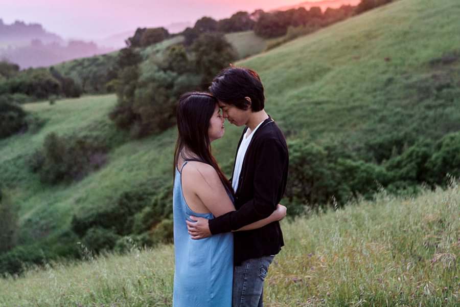 A couple hugs on a mountainside while thinking about engagement anxiety