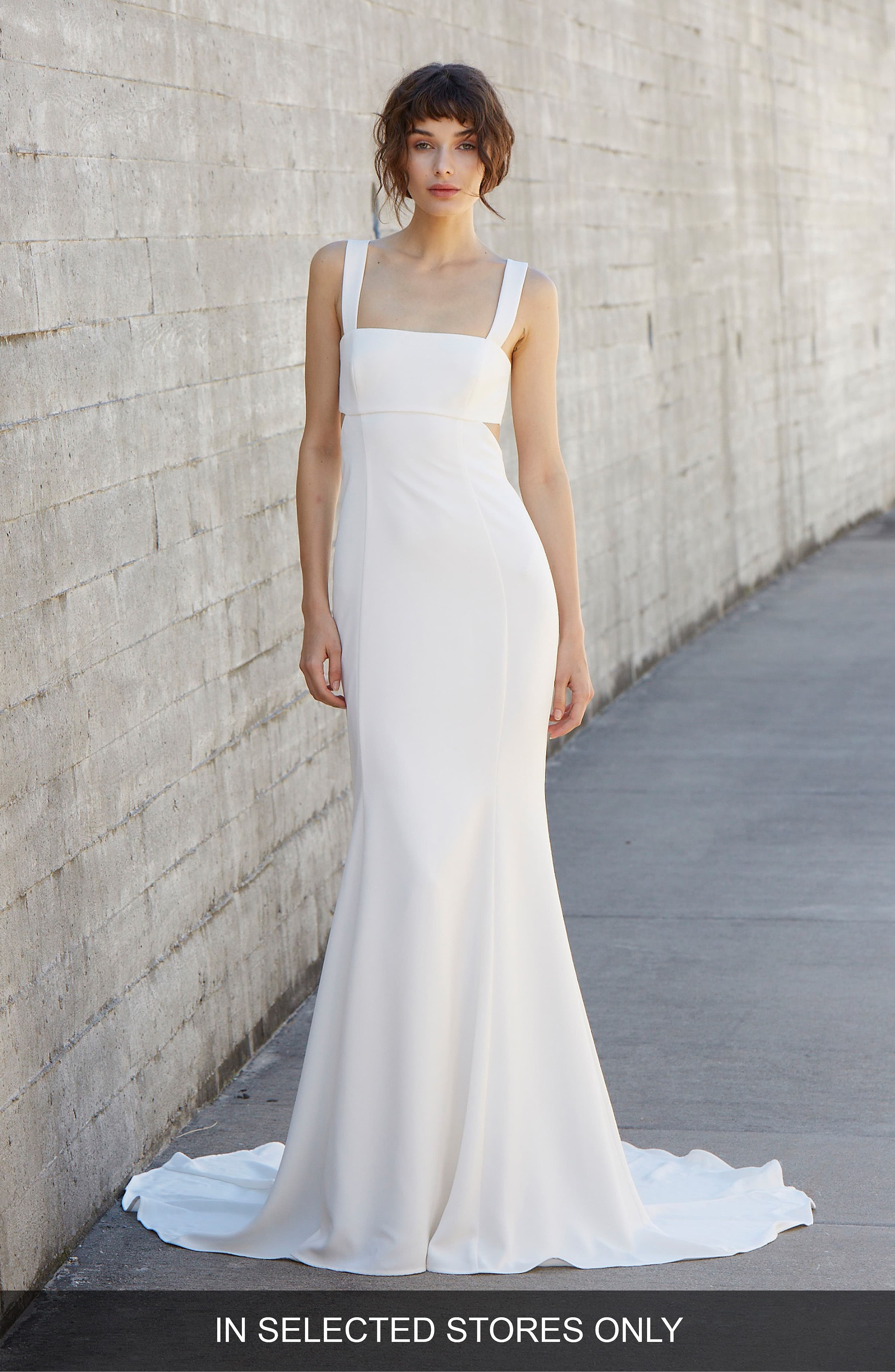 woman with brown hair in an updo wearing a sleeveless cut-out simple white wedding dress