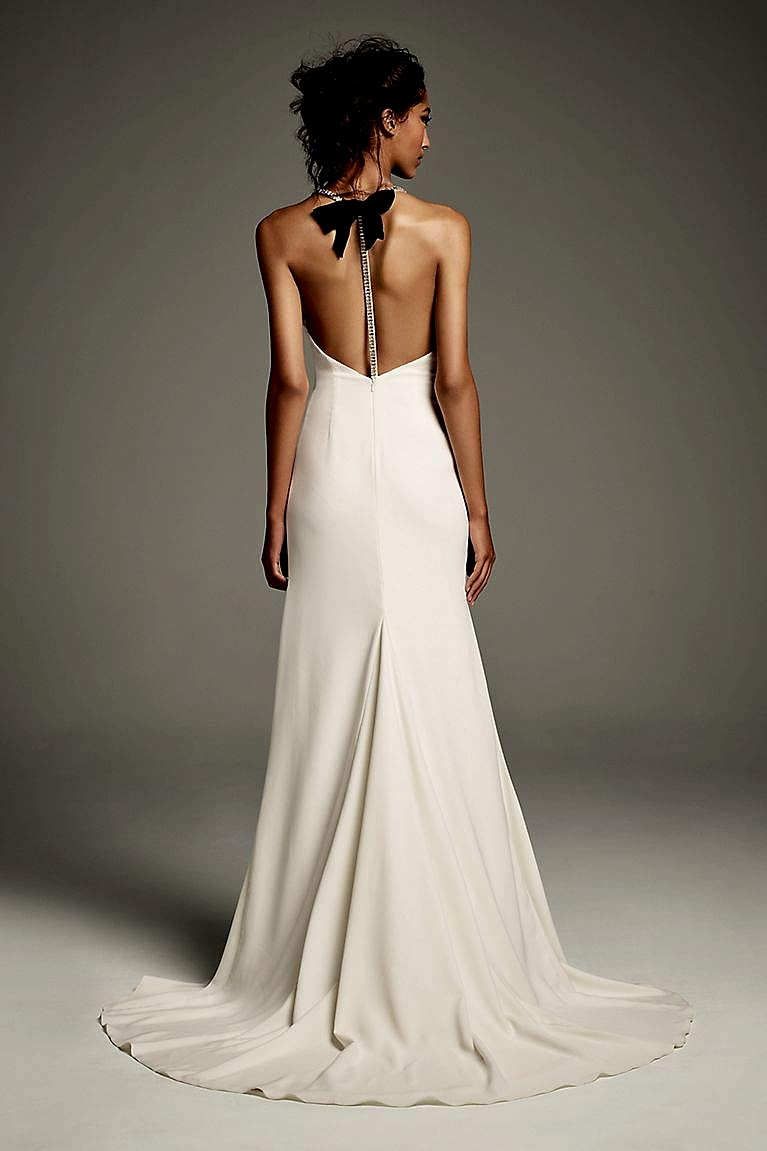woman wearing one of the prettiest wedding dresses with a black bow at the neck of the dress