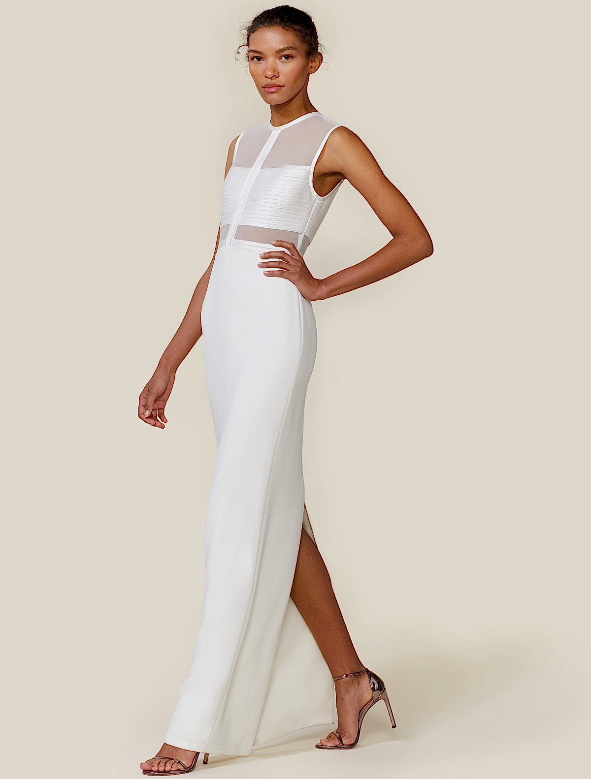 woman wearing a long sheer sleeveless wedding dress with white cutouts