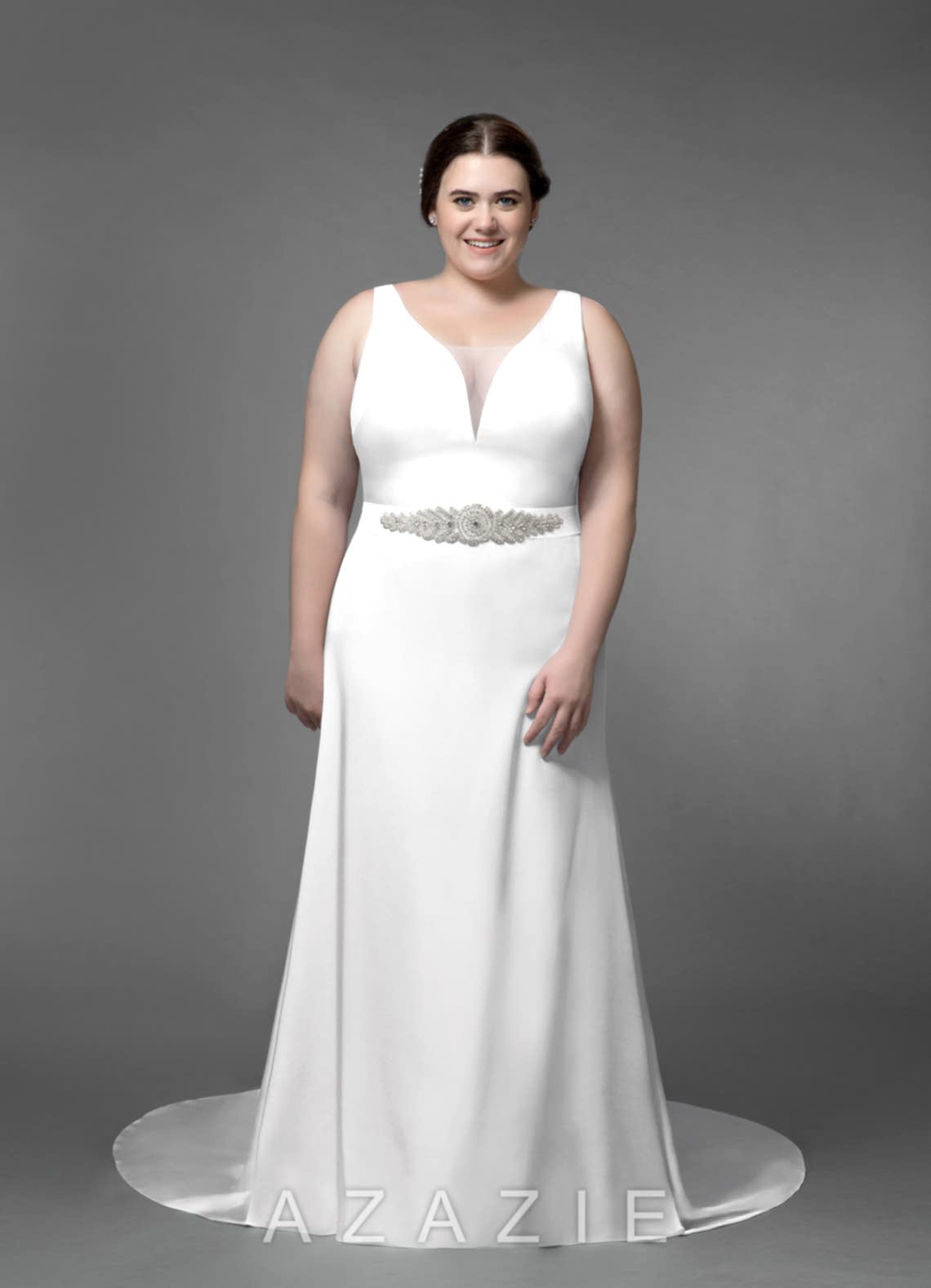 plus size woman wearing a sleeveless belted wedding gown