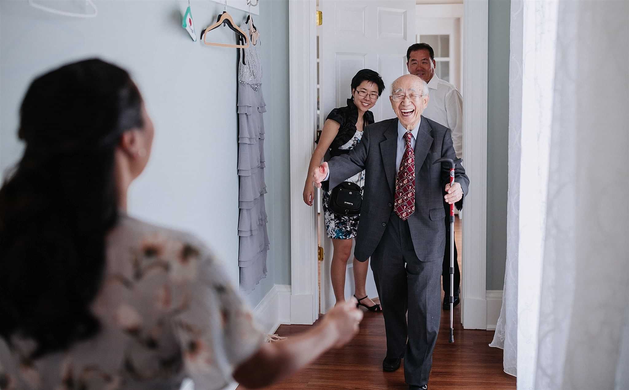 An elderly man smiles as he walks towards a woman.