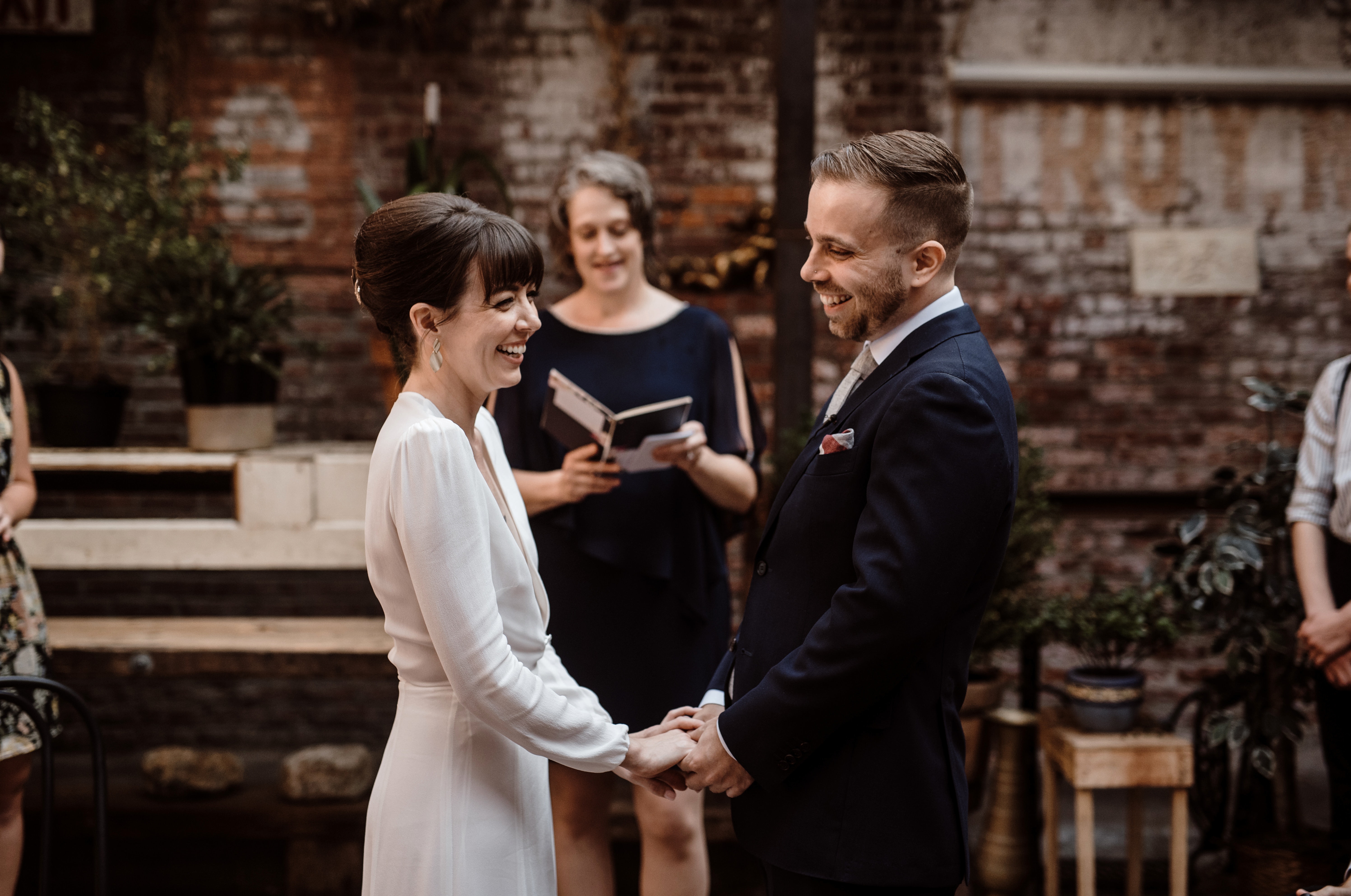 A man and woman laugh and smile during their wedding ceremony.