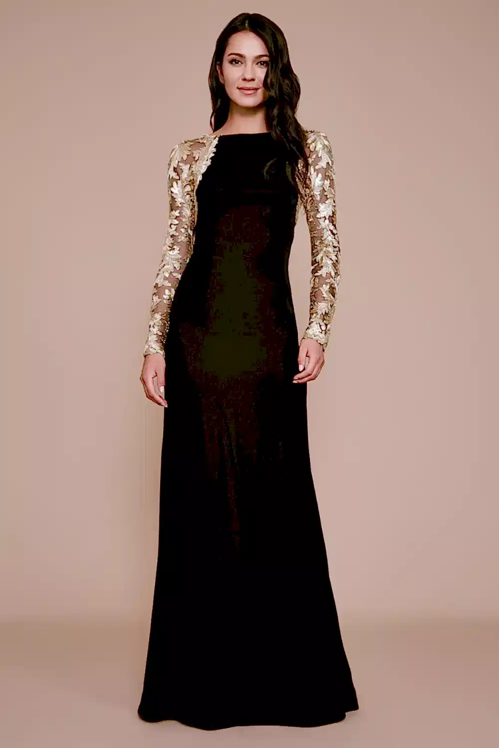 A model wears a full length black gown with lace sleeves.