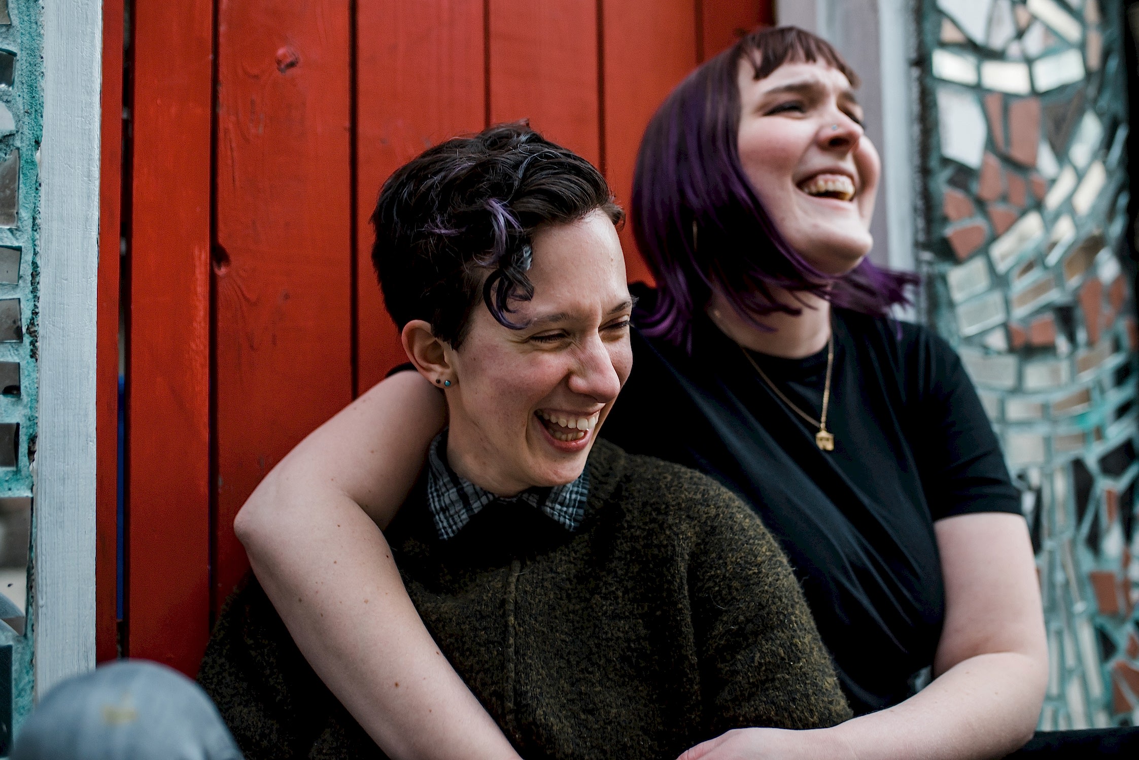 Two persons sit together and laugh.