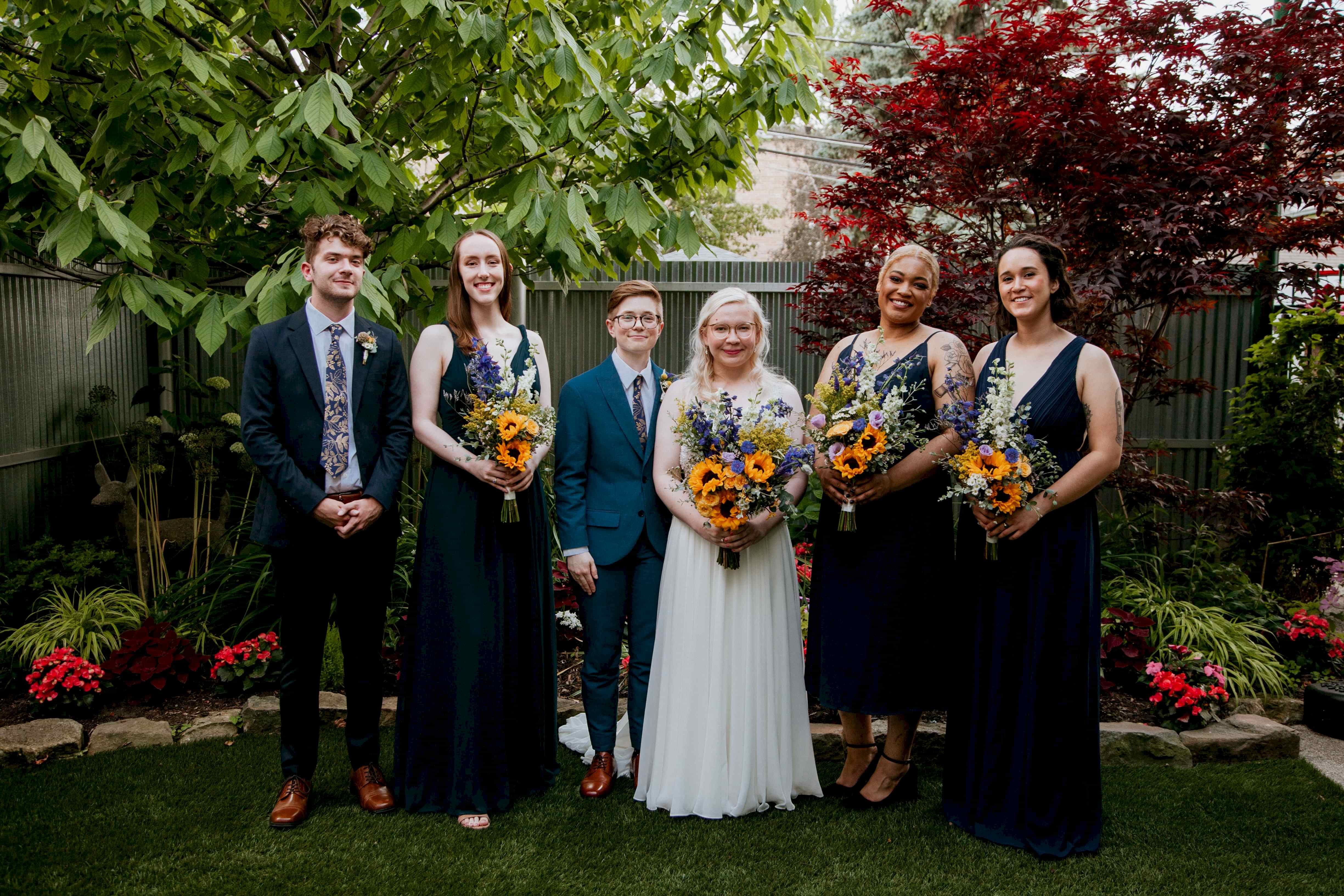 A wedding couple and their wedding party stand in a line.