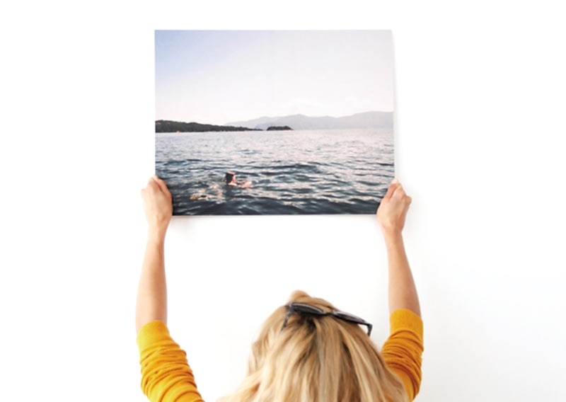 A woman holds up a metal print.