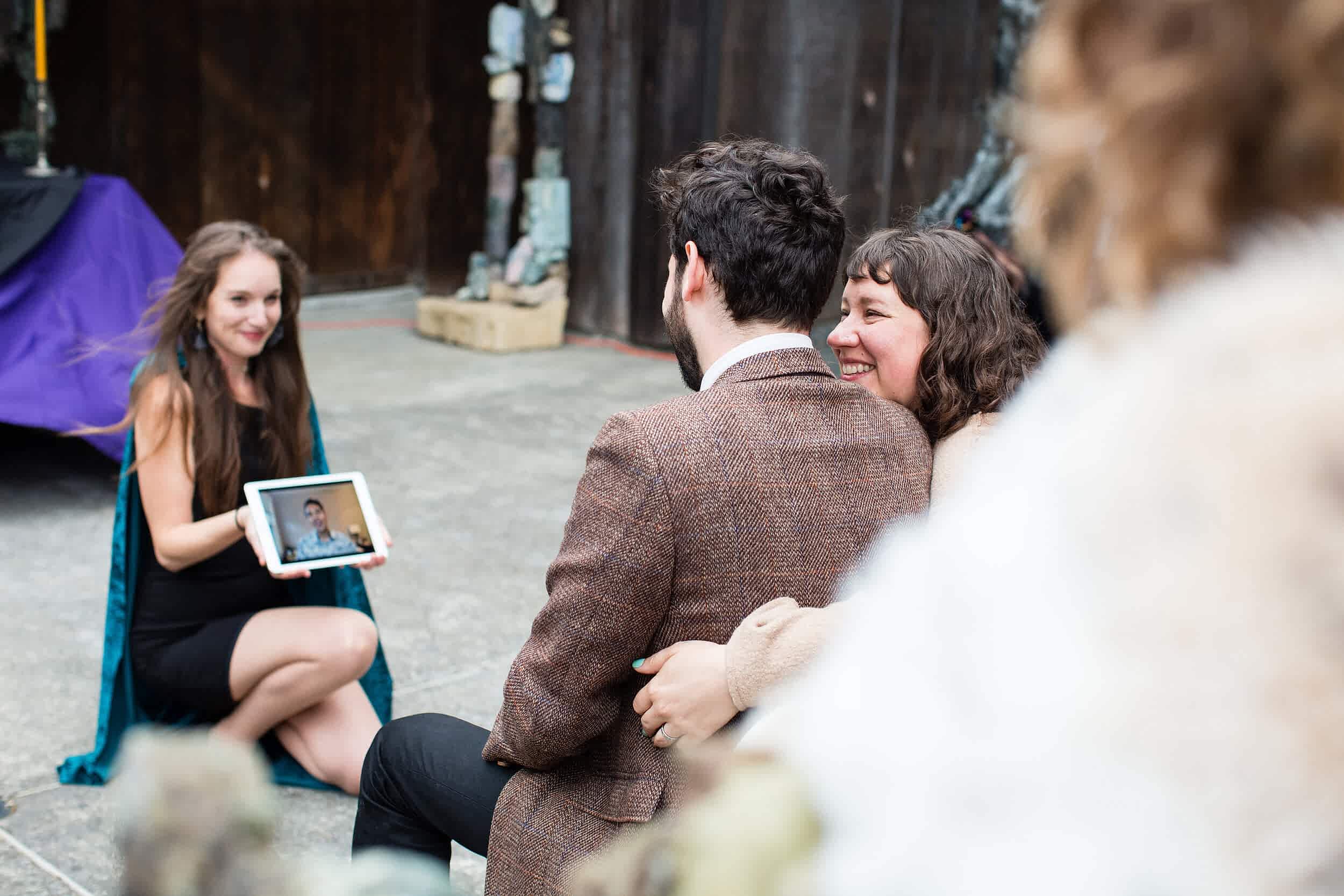A woman shows a couple a Facetime caller on an ipad.