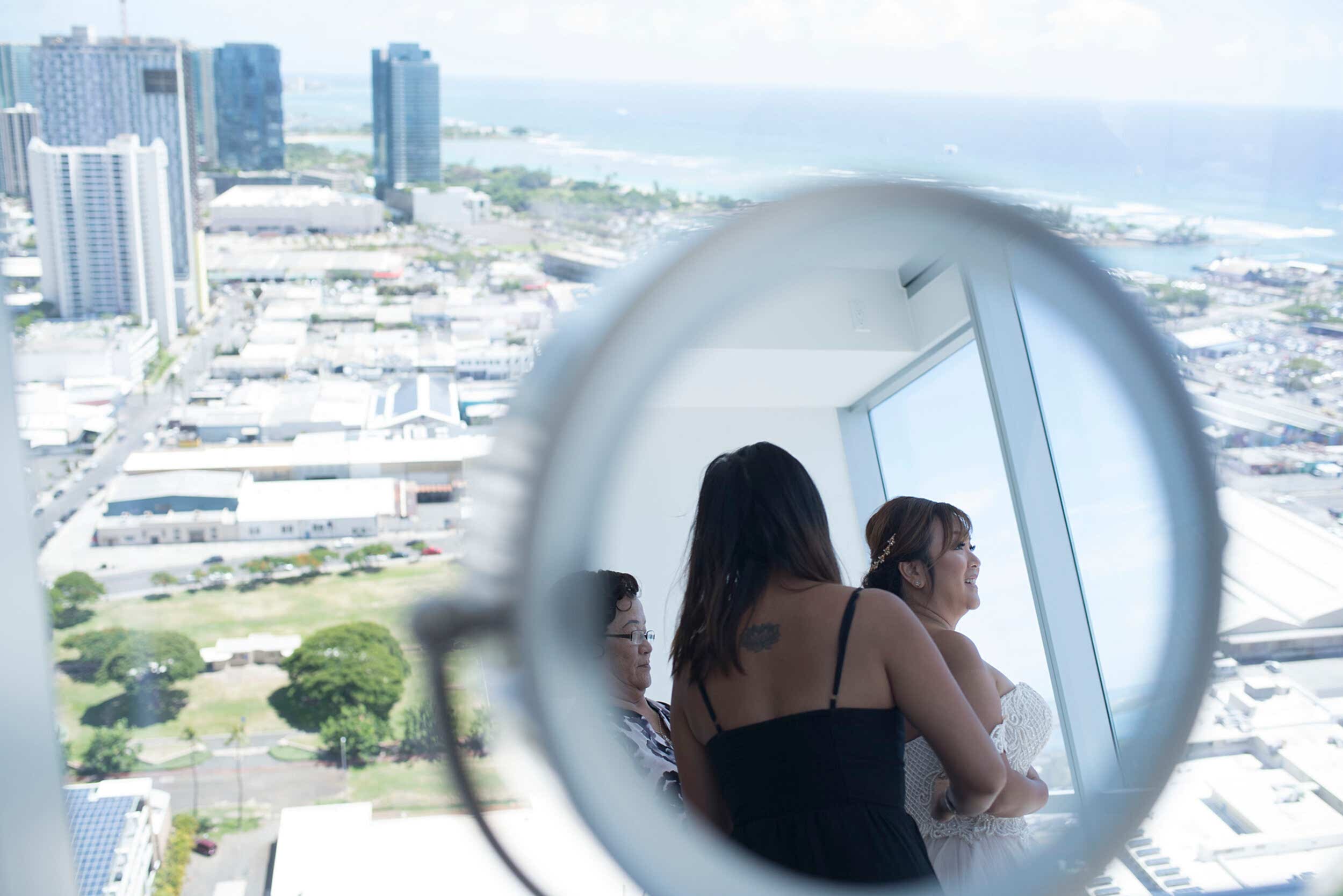 A mirror reflection of a woman putting on her wedding dress.