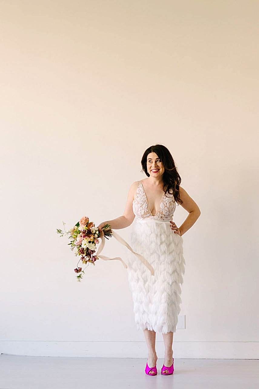 Meg stands and holds a flower bouquet.