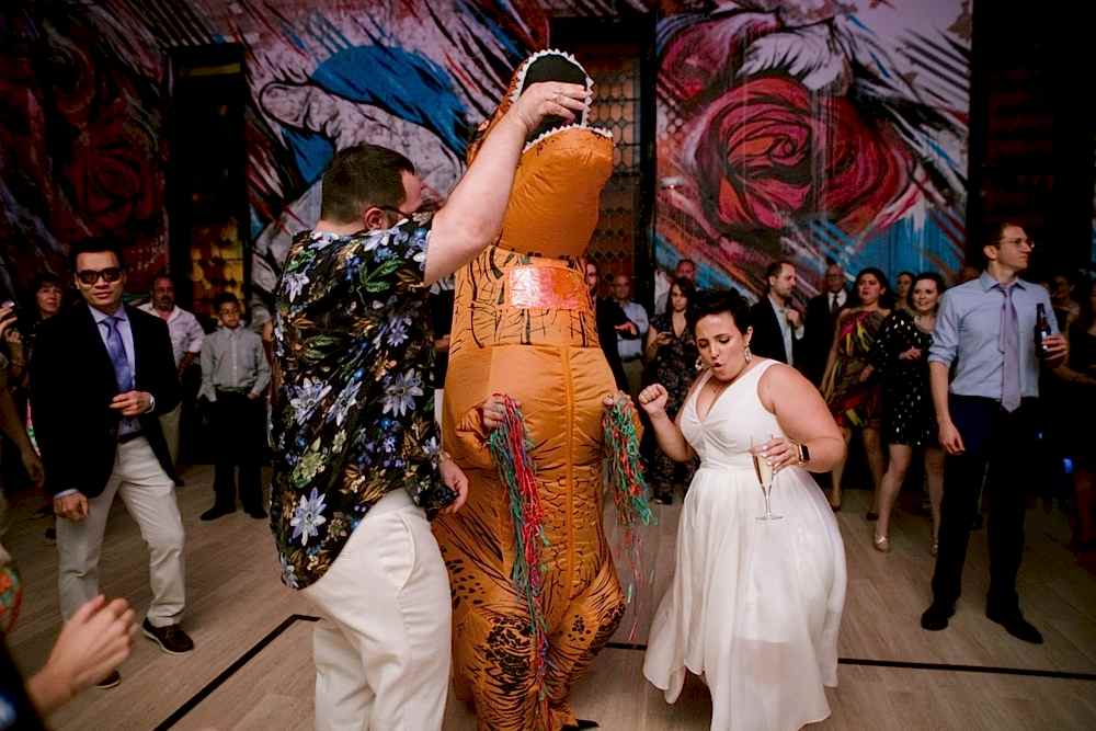 A wedding couple dance during their reception with a T-Rex