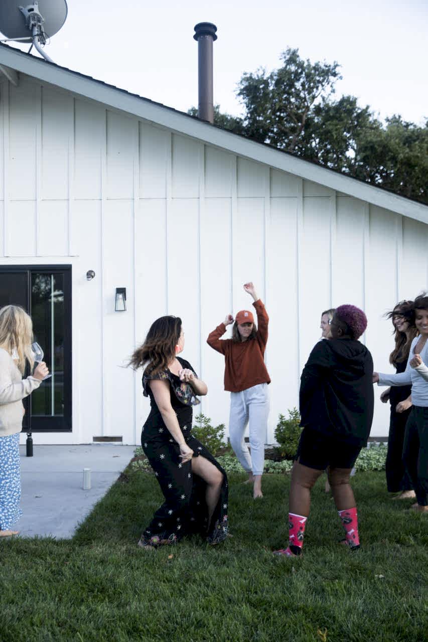 Womxn dancing in a back yard.