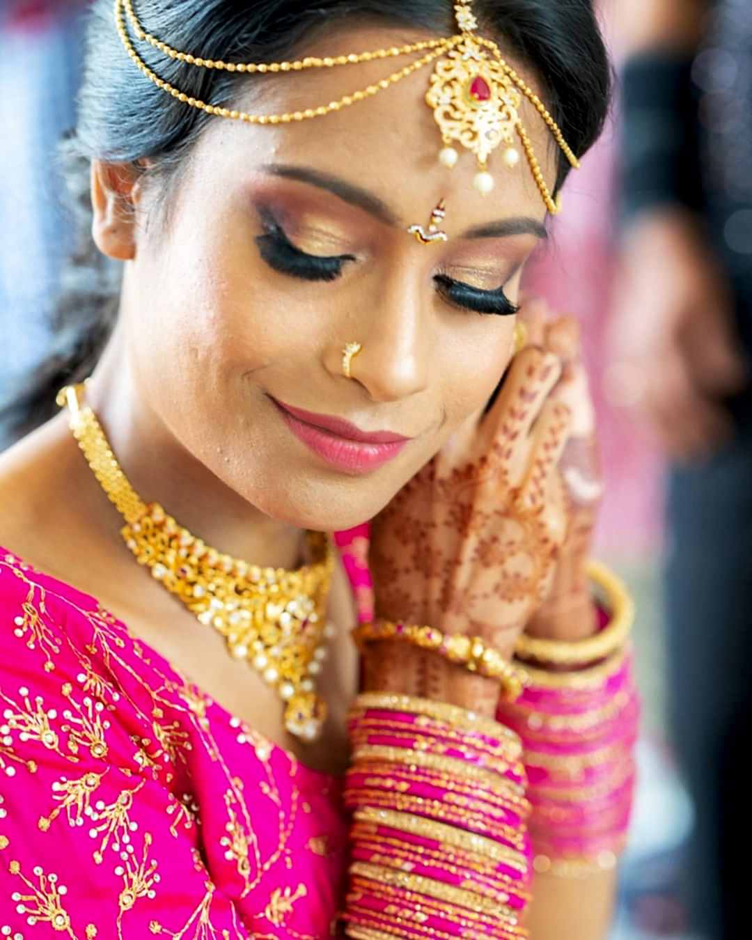 A bride smiles as she puts on an earring.