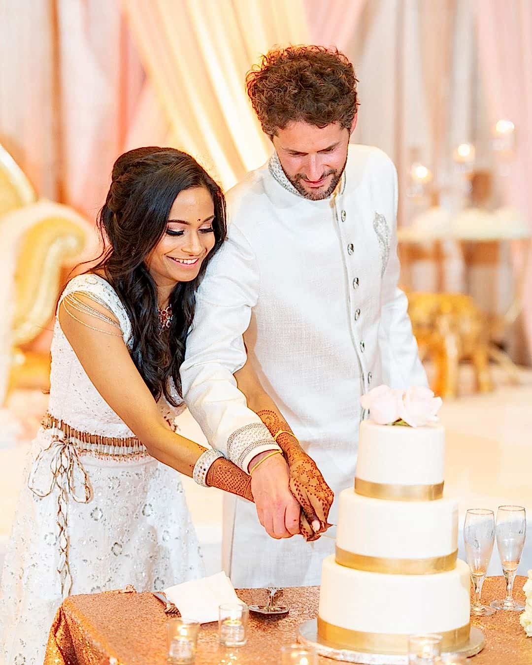 A wedding couple cut the cake together.