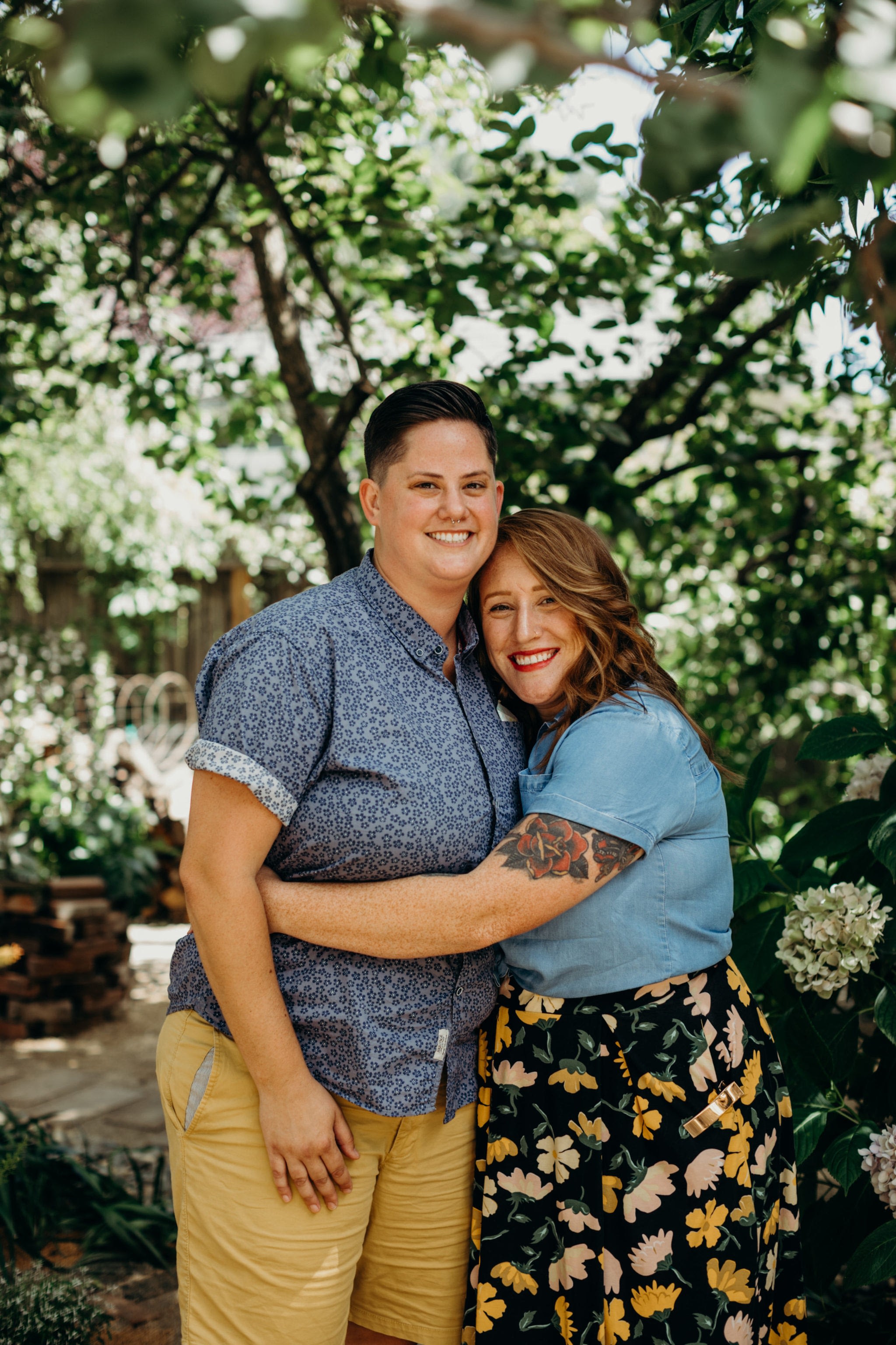 A couple embrace while standing in a garden.