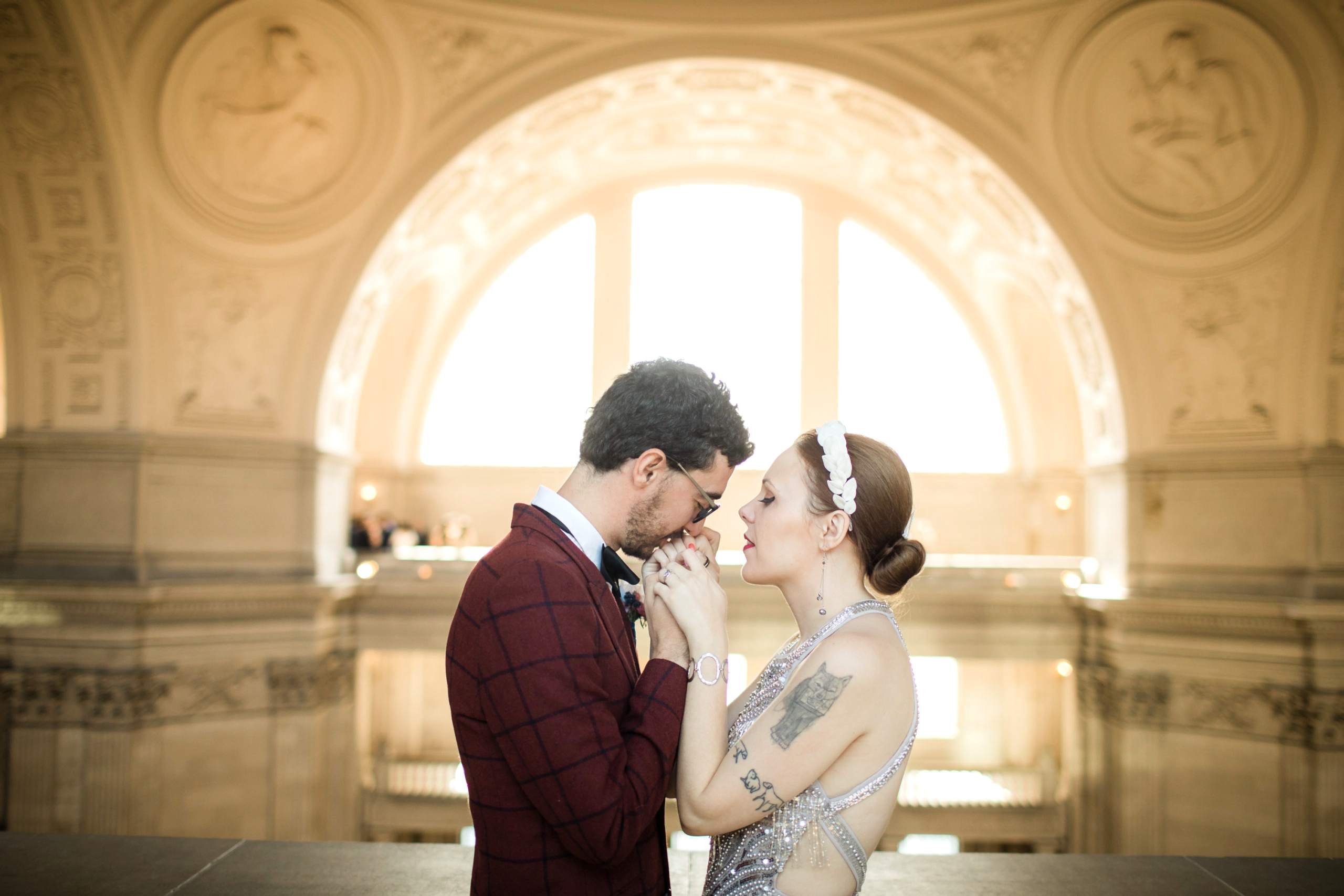 A wedding couple hold hands and kiss while at City Hall.