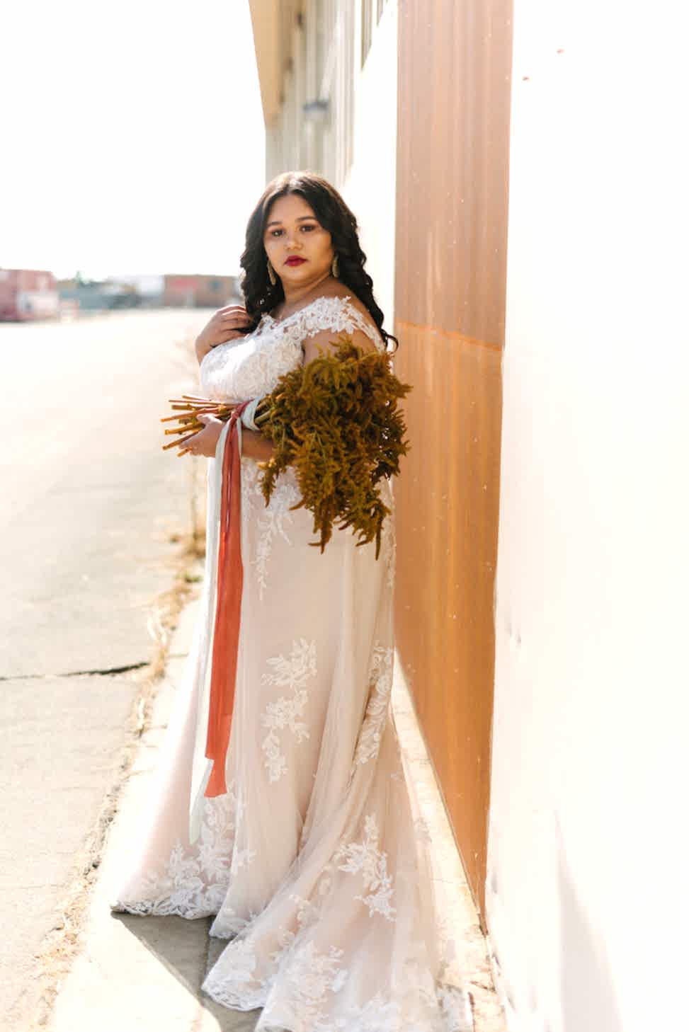 A woman holds a bouquet while wearing Maggie Sottero wedding dress style 'Liesl Lynette.'