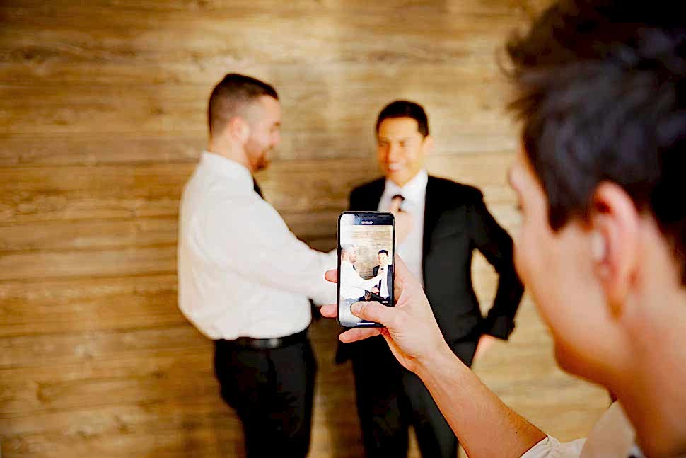 Someone records as one man helps another with his tie.