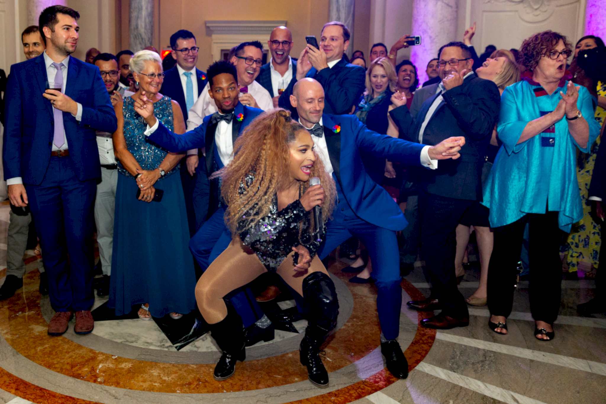 Two grooms dance with their wedding singer.