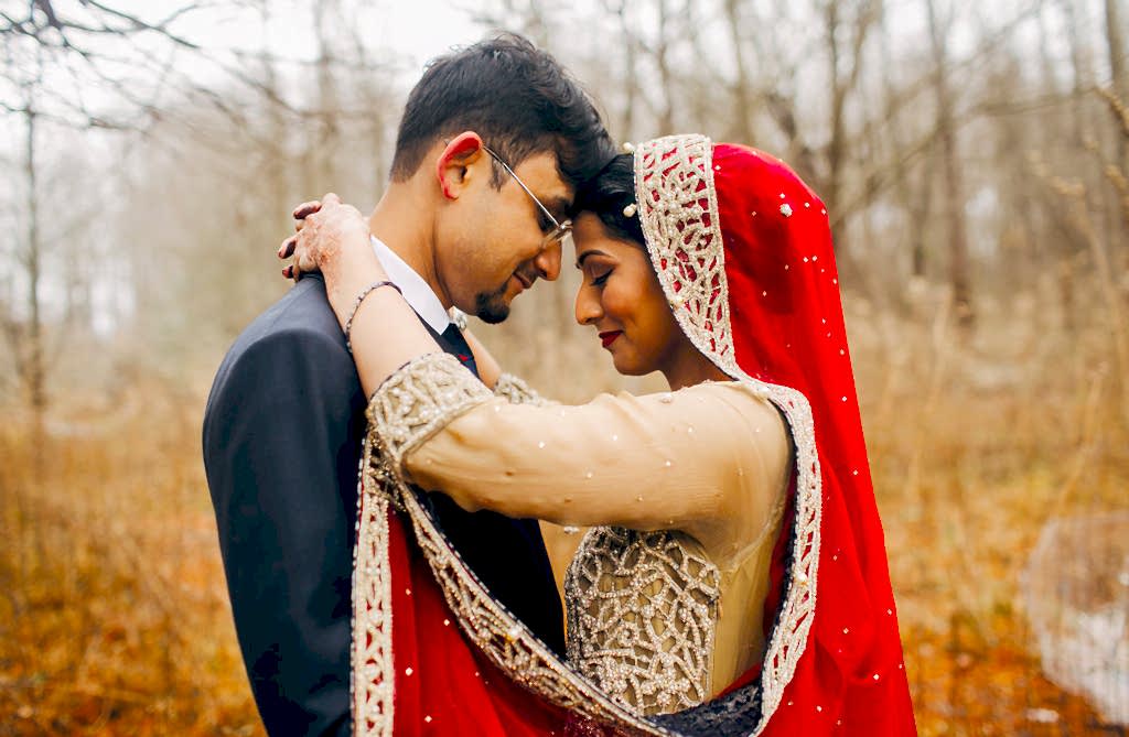 A wedding couple hugs while in the forest.