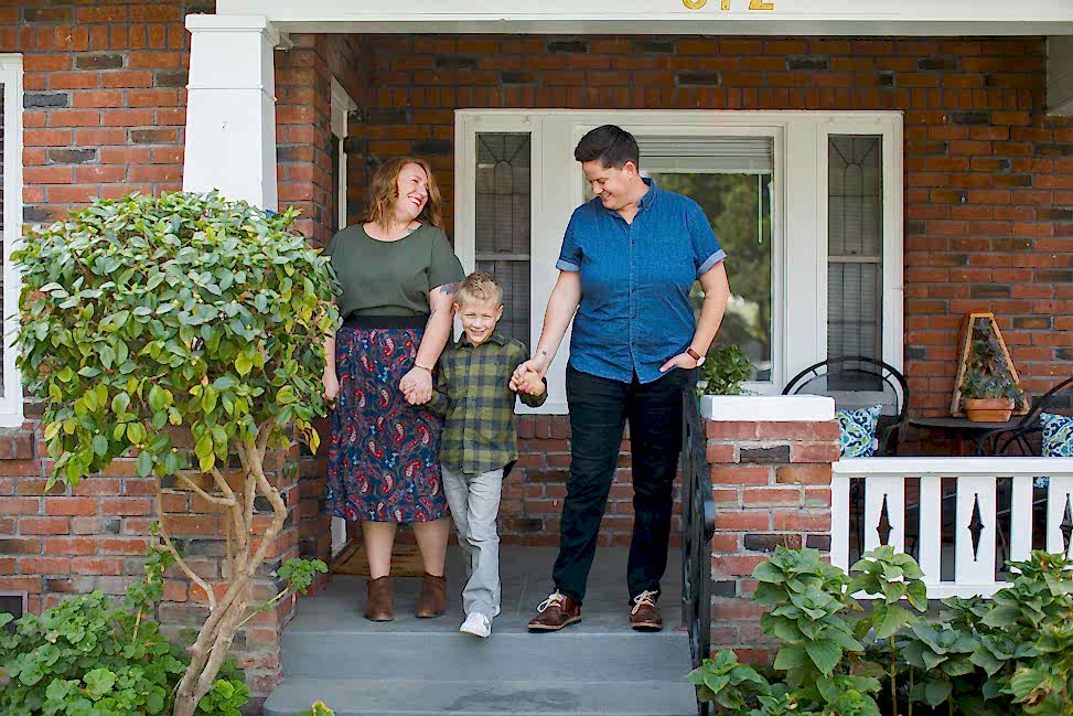 Two parents holding hands with their child in the middle.
