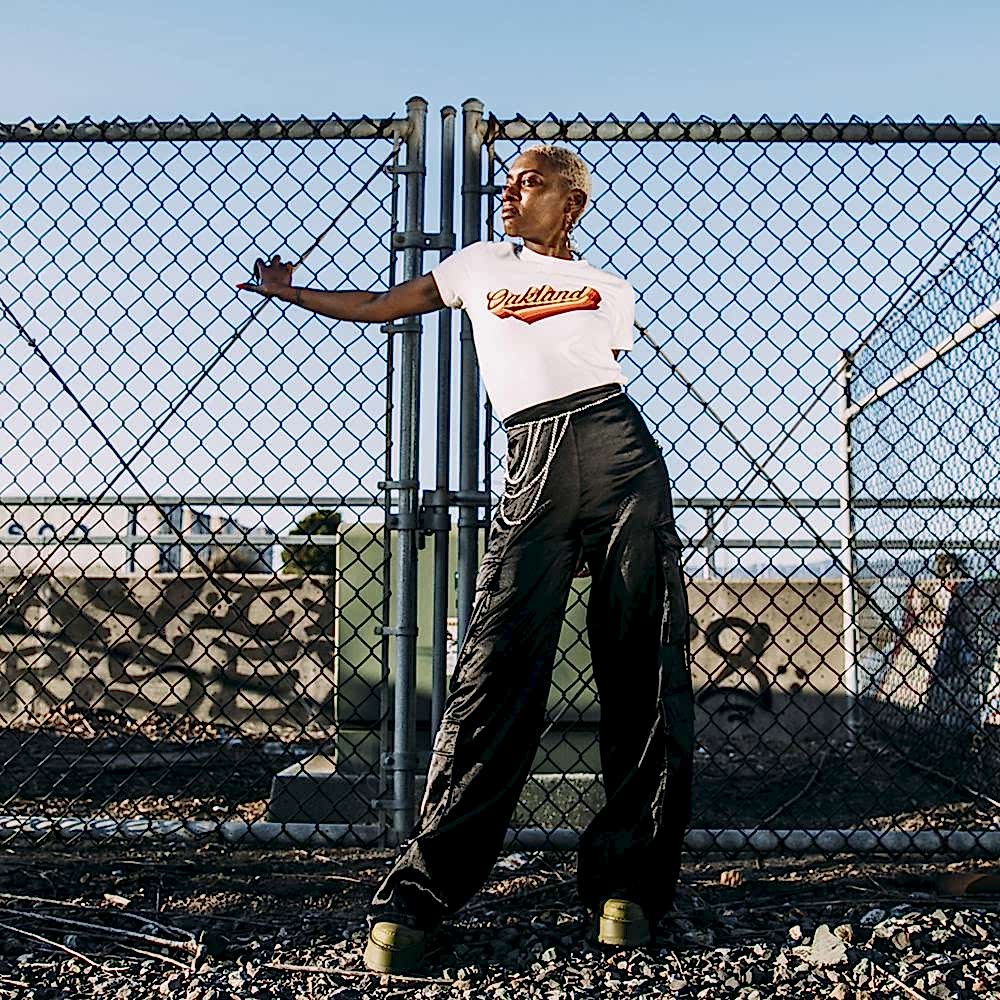 A woman poses wearing a t shirt with Oakland printed on it.