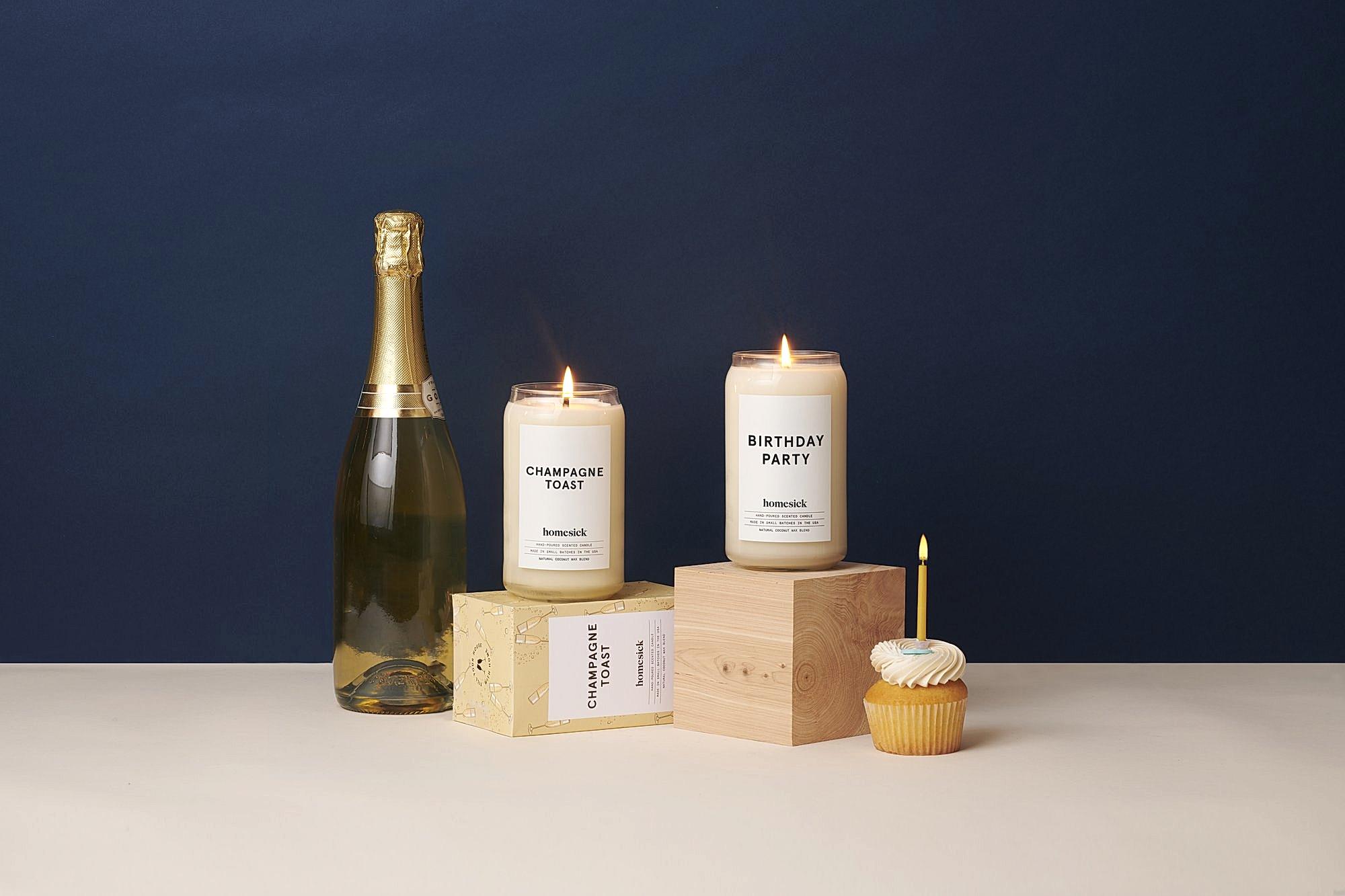 a bottle of champagne with two candles and a cupcake