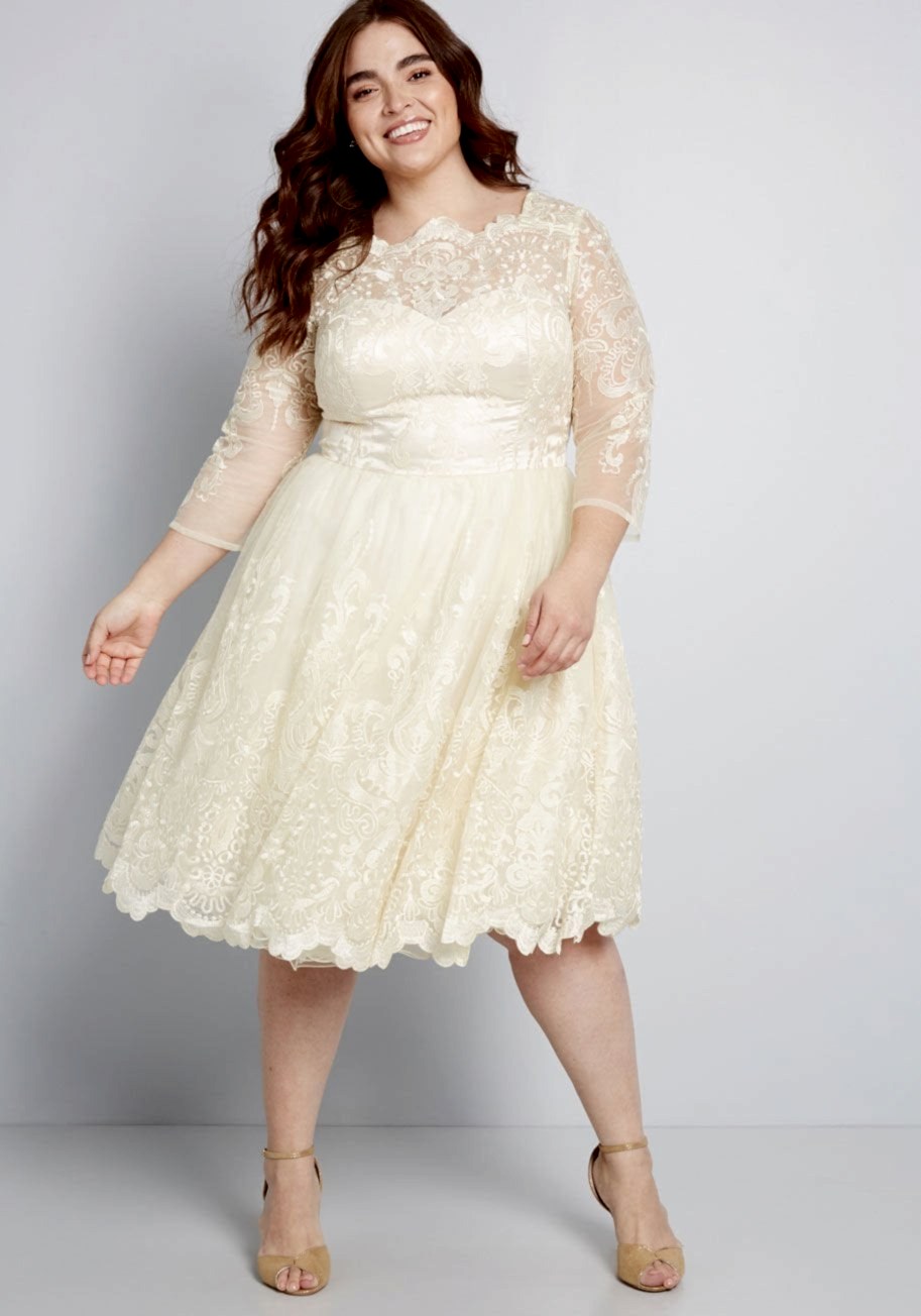Woman with dark hair in short cream lace wedding dress