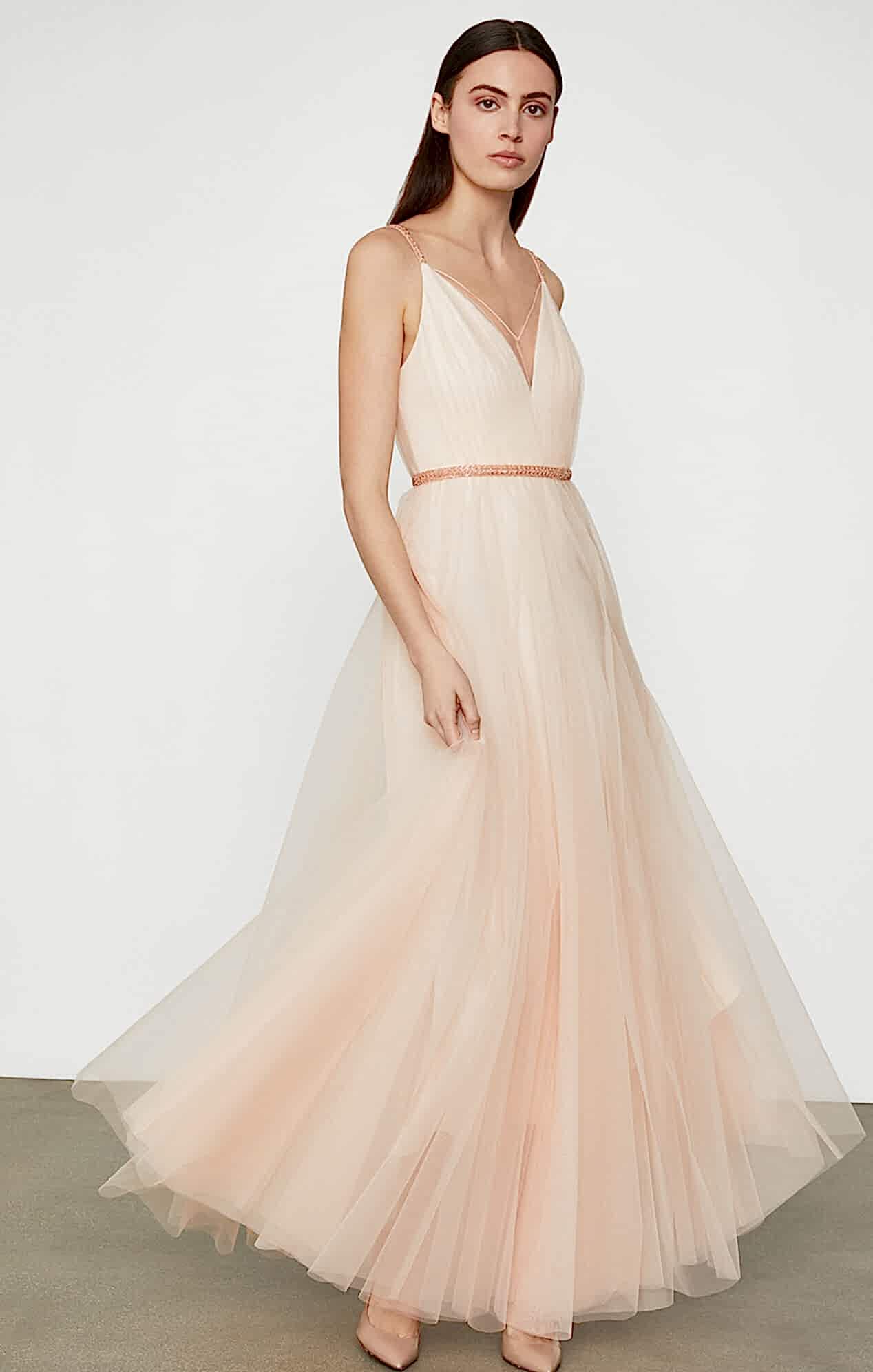 Woman with dark hair in blush colored flowy ballerina style floor length gown