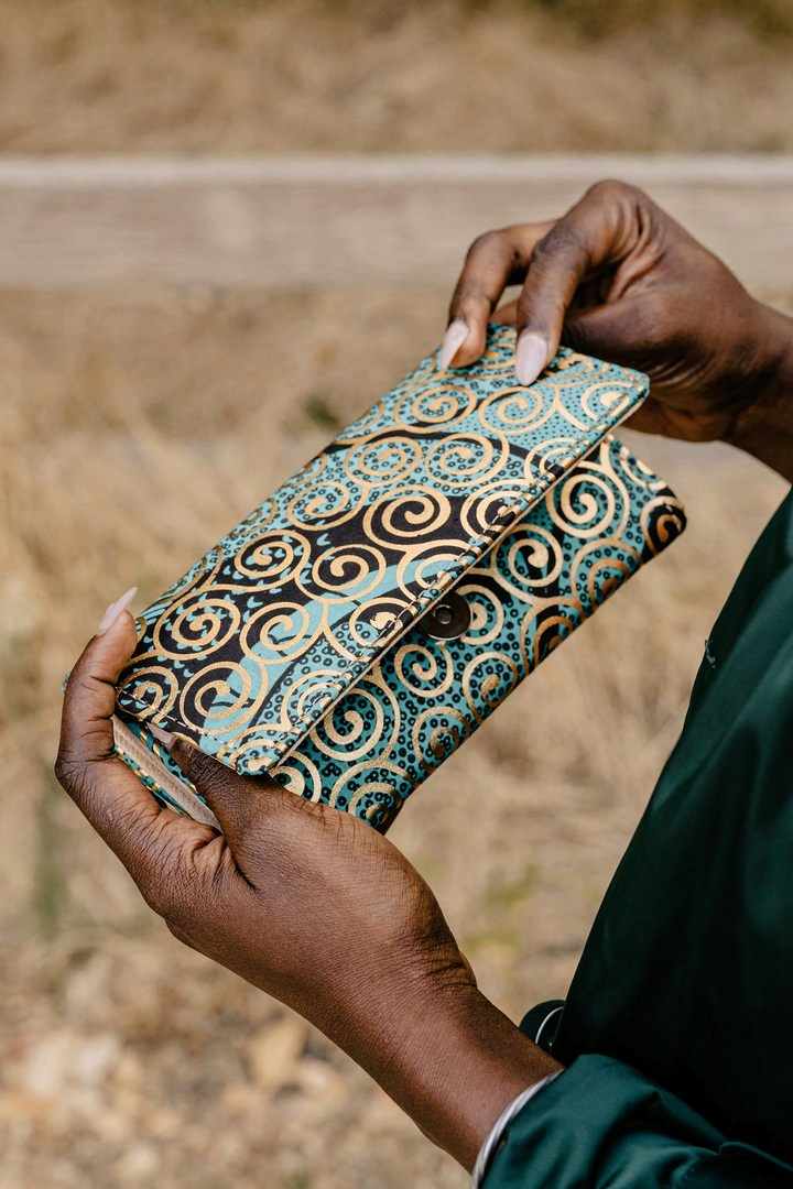black womxn holding up a printed leather wallet