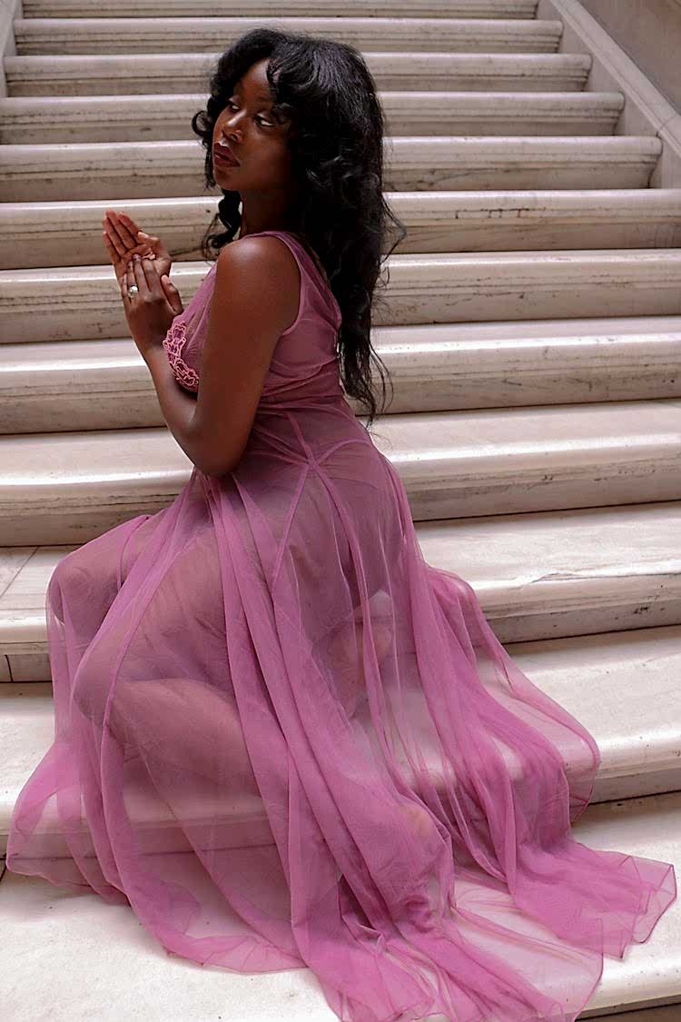 black womxn wearing a transparent nightgown sitting on the stairs