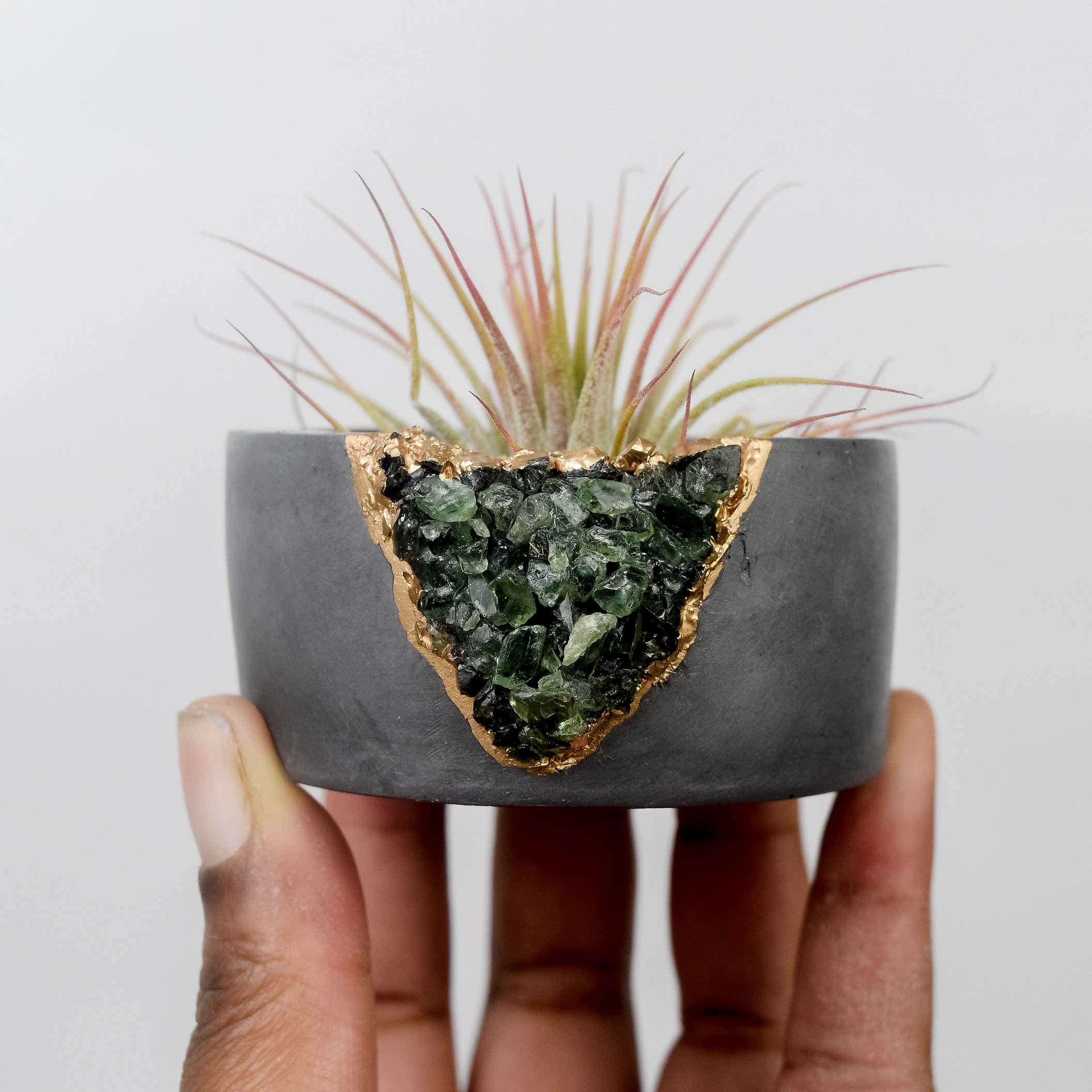 someone holding up a concrete planter with geode crystals exposed