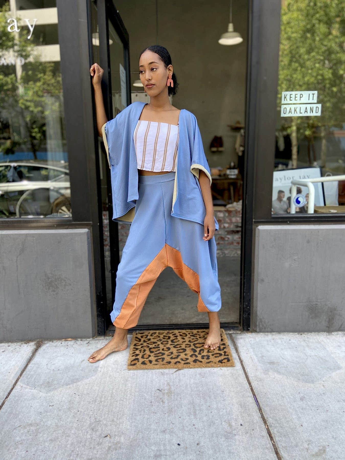 woman leaning in doorway wearing a matching periwinkle and orange two piece set