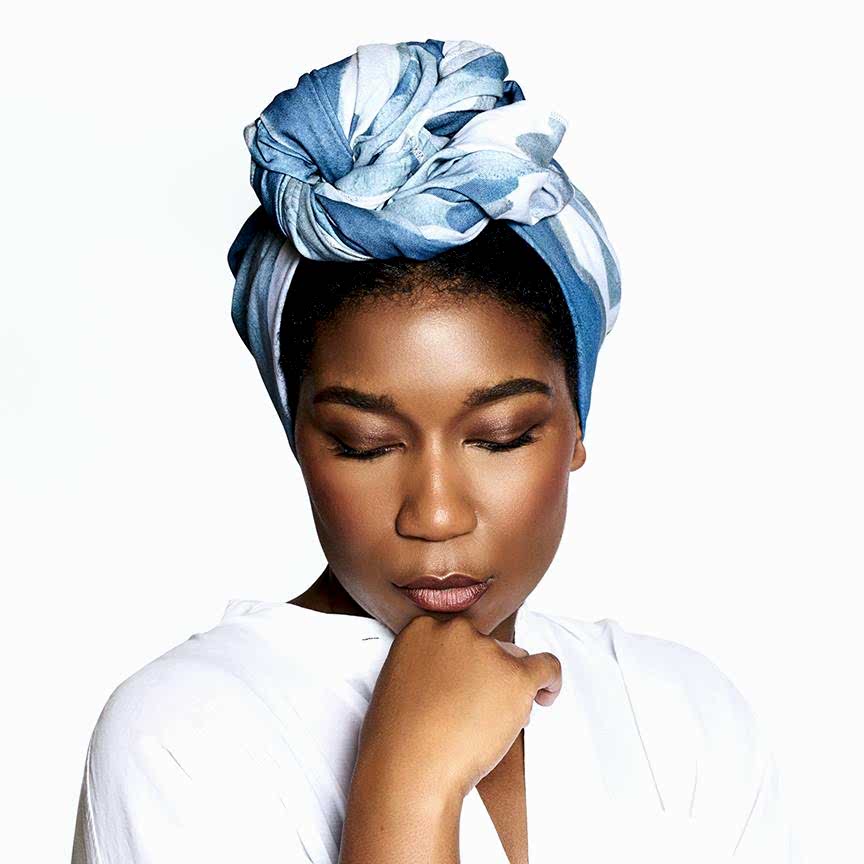 black woman wearing a headwrap with her chin on her hand and her eyes closed