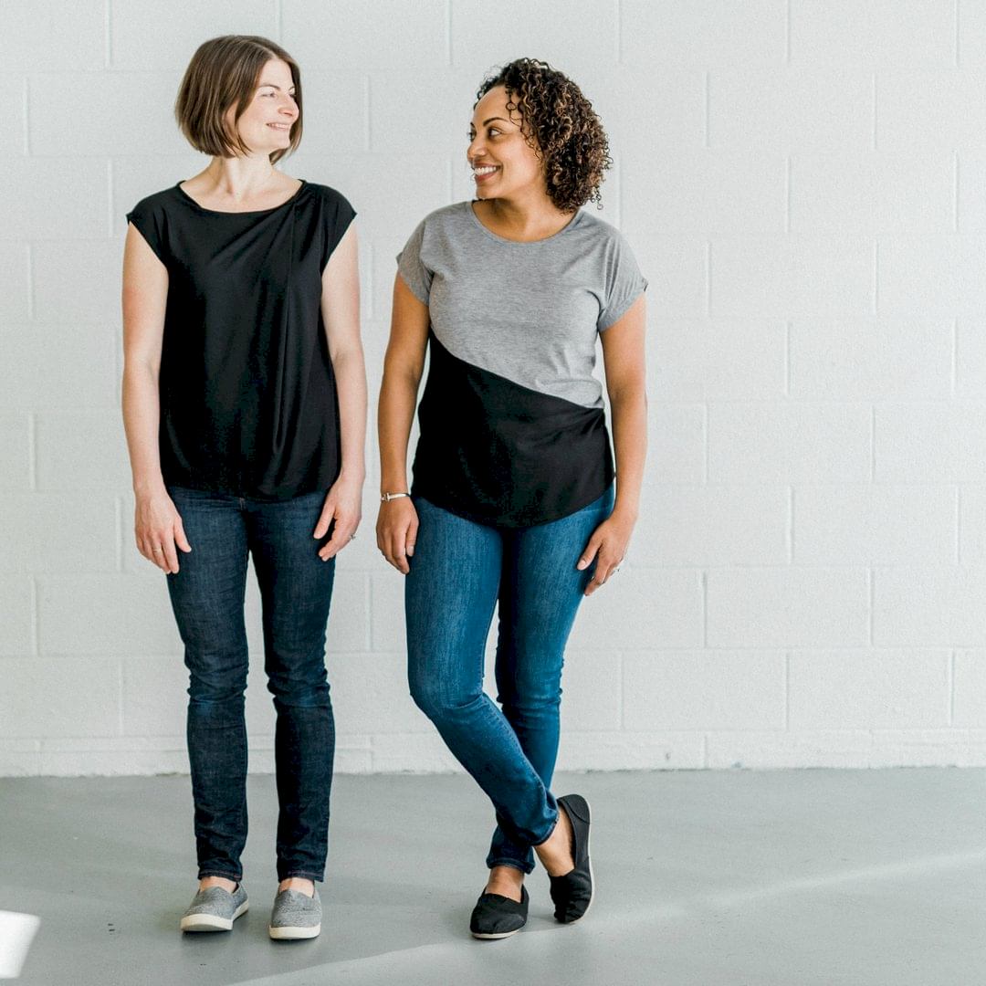 one white womxn and one black womxn smiling at each other wearing black and grey shirts